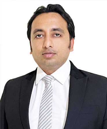 Portrait of Mr. Digant Sharma in a dark suit, white shirt and patterned tie, photographed against a plain white background.