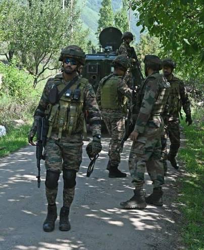 Illustrative photograph: personnel moving along a sunlit rural road, one in the foreground observing the surroundings.